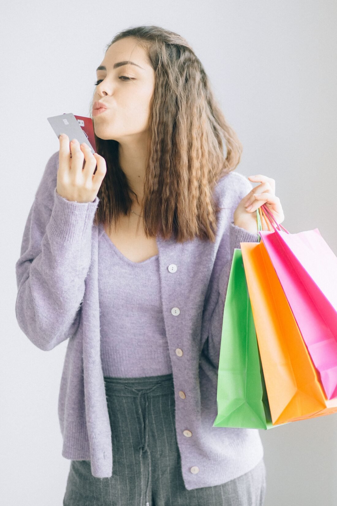 Mulher com sacolas de compras e cartão de crédito com cashback