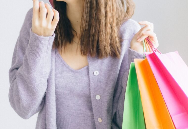 Mulher com sacolas de compras e cartão de crédito com cashback