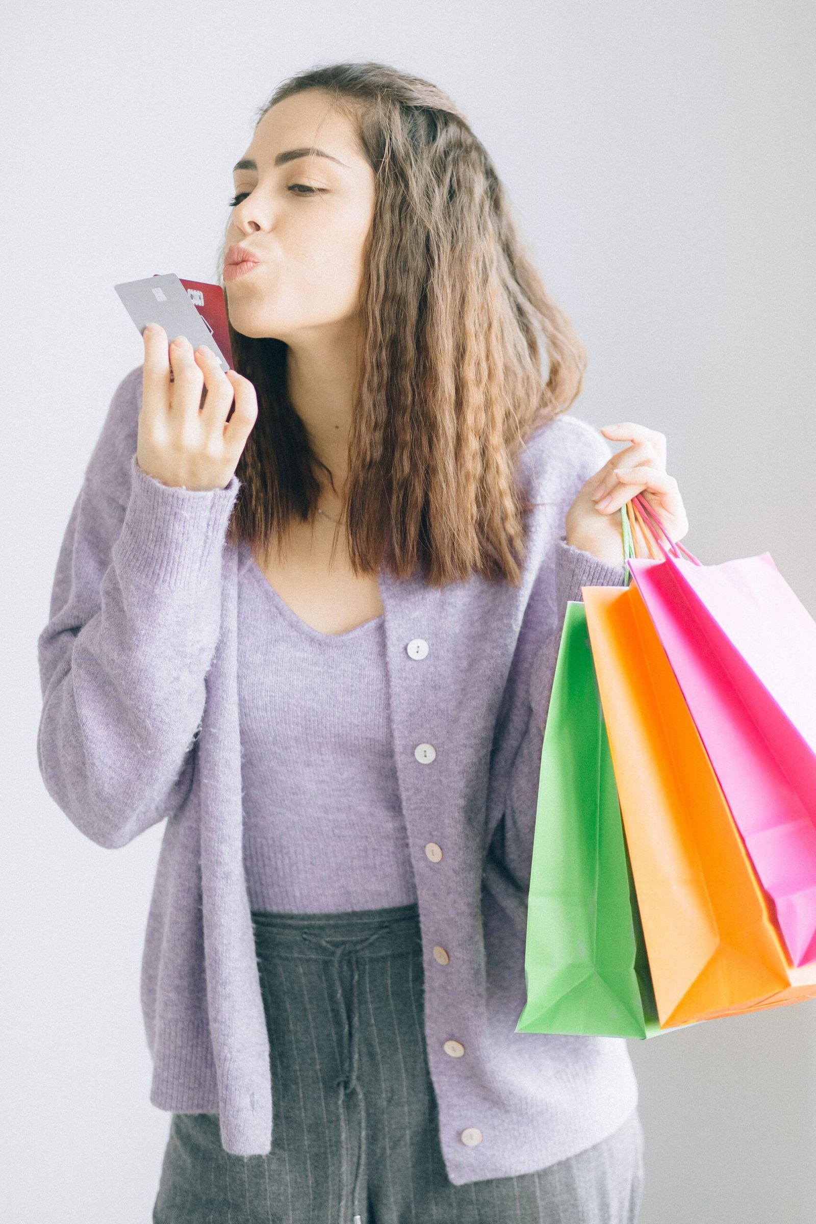 Mulher com sacolas de compras e cartão de crédito com cashback