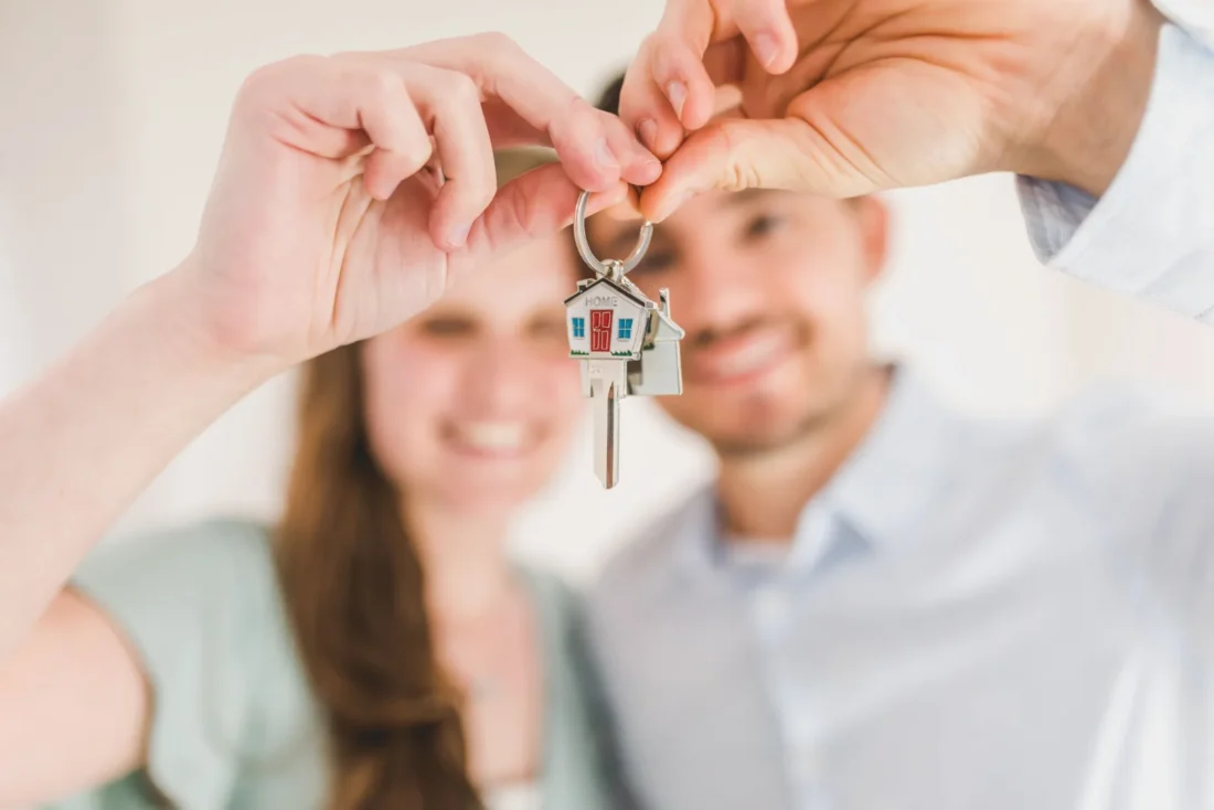 Casal feliz segurando chave da casa própria após financiamento