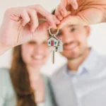 Casal feliz segurando chave da casa própria após financiamento