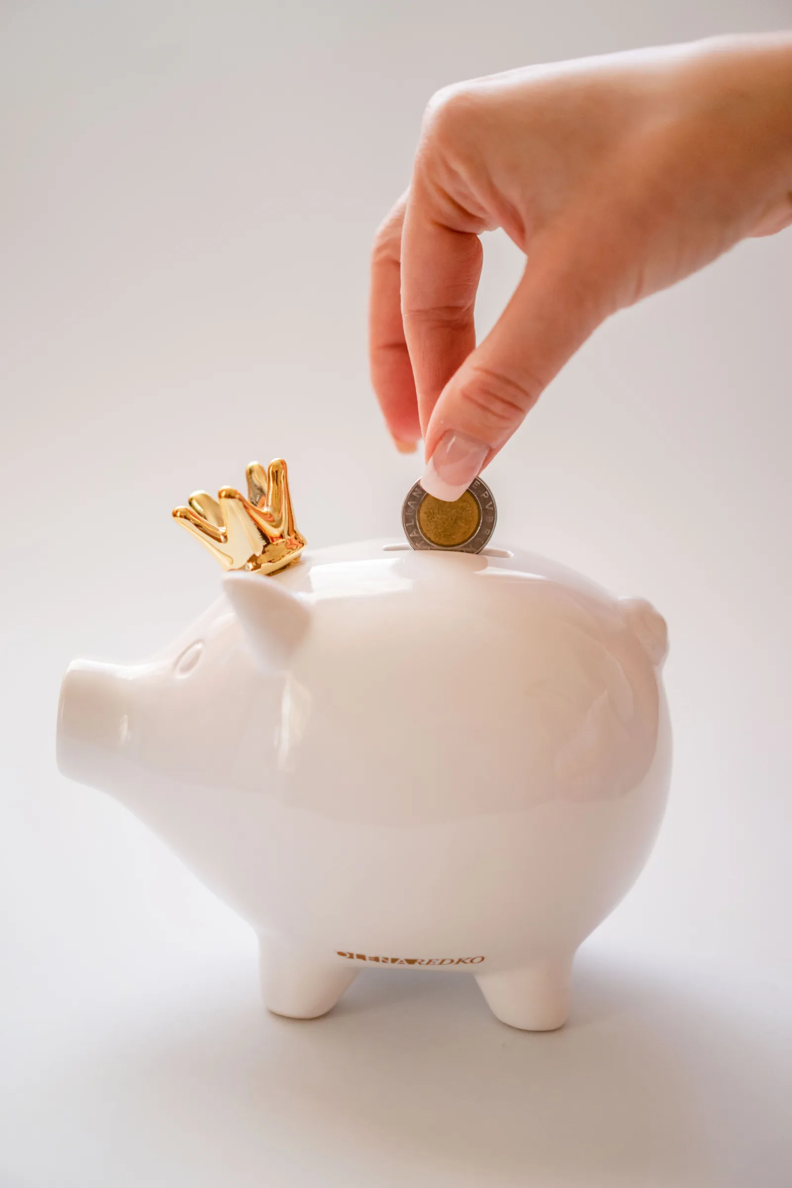 Mão colocando moedas em cofrinho representando diversificação de renda