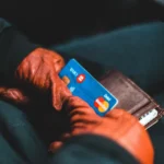 Pessoa segurando cartão de crédito azul e branco