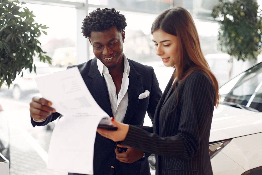 Cliente e consultora lendo os detalhes de um contrato de financiamento de veículo em uma concessionária Cliente e consultora lendo os detalhes de um contrato de financiamento de veículo em uma concessionária