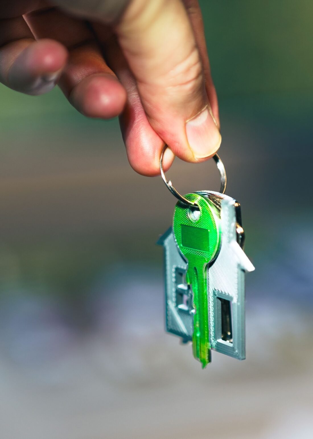 Mão segurando chaveiro em formato de casa, representando a simulação do financiamento da casa própria Mão segurando chaveiro em formato de casa, representando a simulação do financiamento da casa própria